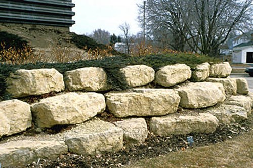 A nicely done wall out of large pieces of Lannon stone.  The Junipers will fall over the wall softening the edge.